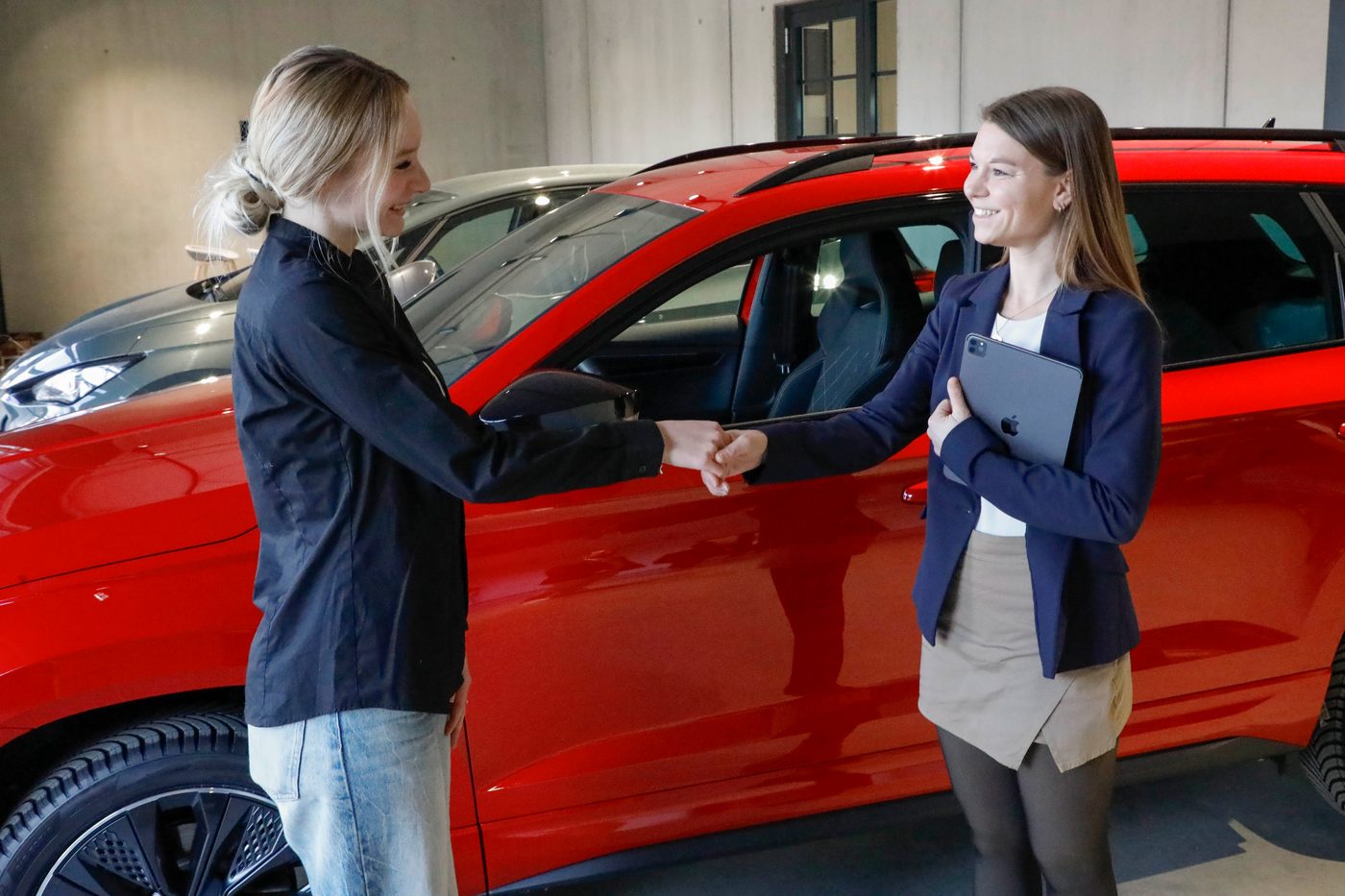 Handschlag bei der Fahrzeugübergabe vor einem Neuwagen